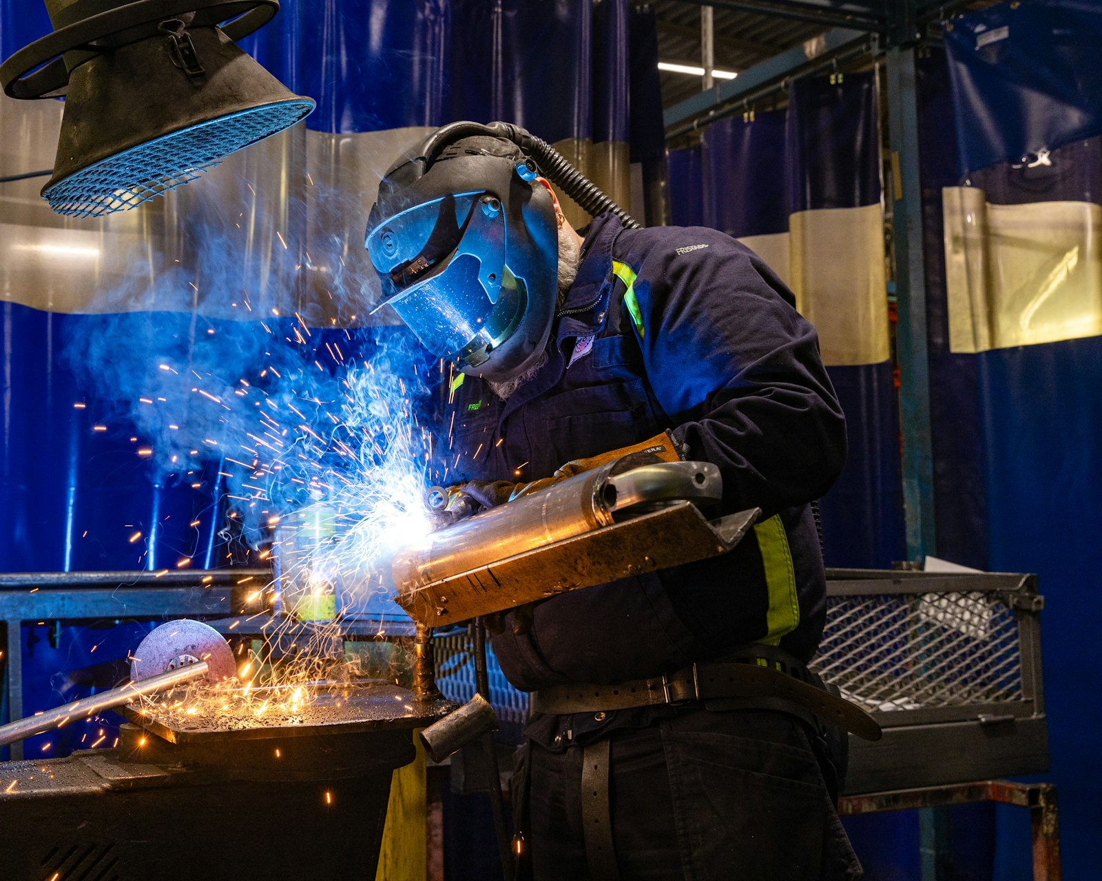 Soudeur casqué en plein travail, dans une gerbe d'étincelles