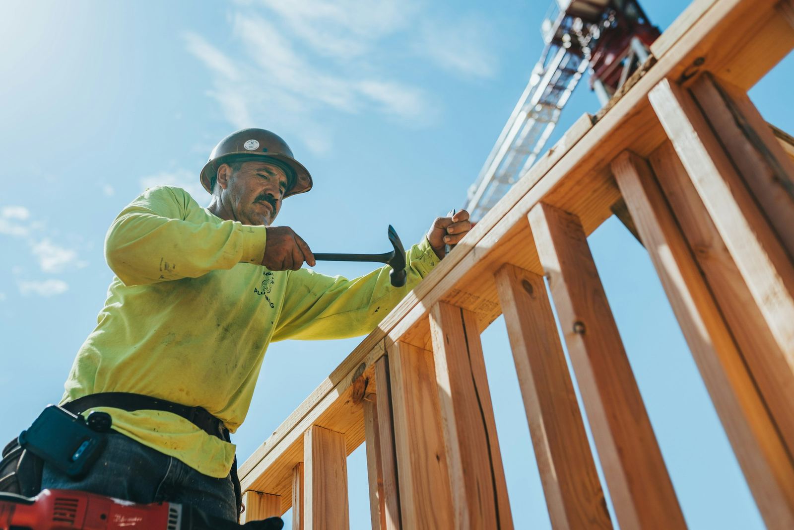 Charpentier casqué qui assemble une ossature bois sur un chantier
